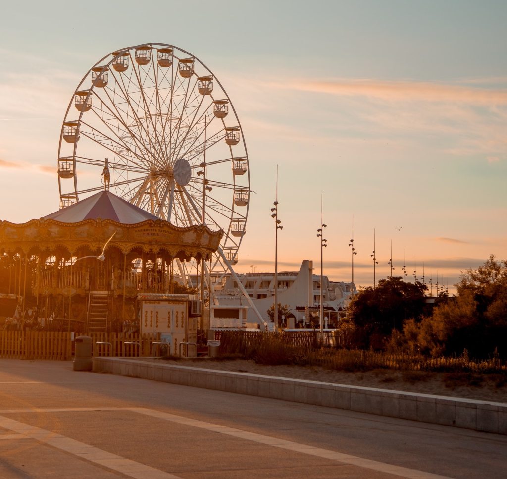 empty fair grounds at sunset with a large ferris wheel and carrousel 